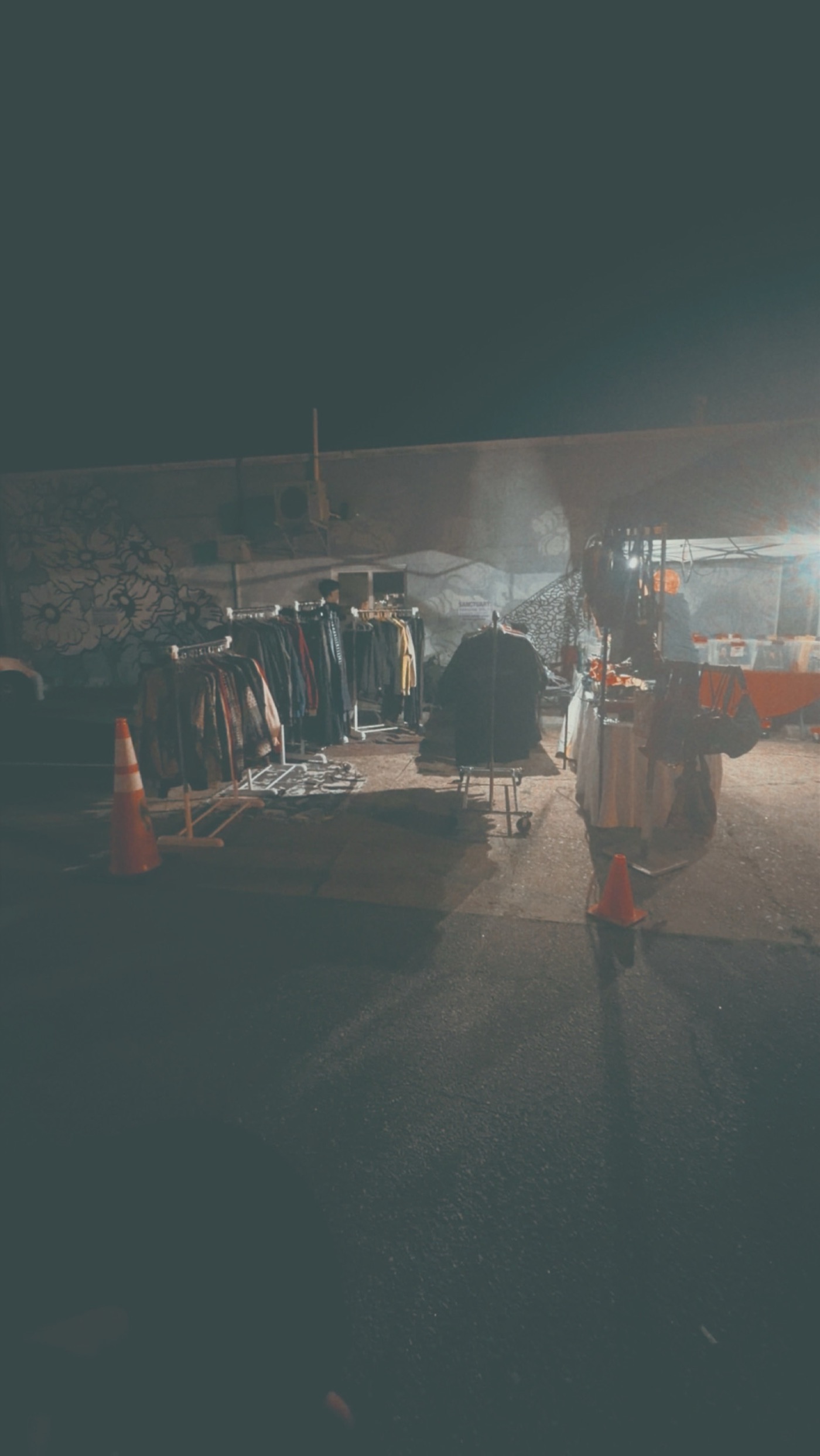 Clothing racks against the mural wall at night